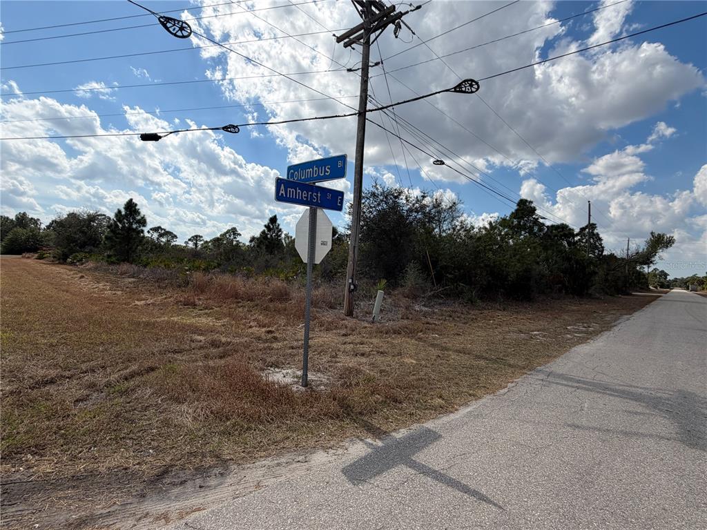 A street sign at the intersection of Columbus Boulevard and Amherst Street in a grassy area — 522 COLUMBUS BOULEVARD S, LEHIGH ACRES, FL