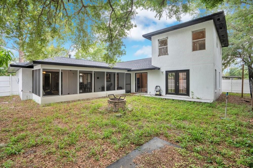 The exterior of a two-story white house features a screened-in porch and a fire pit — 5533 PENTAIL CIRCLE, TAMPA, FL