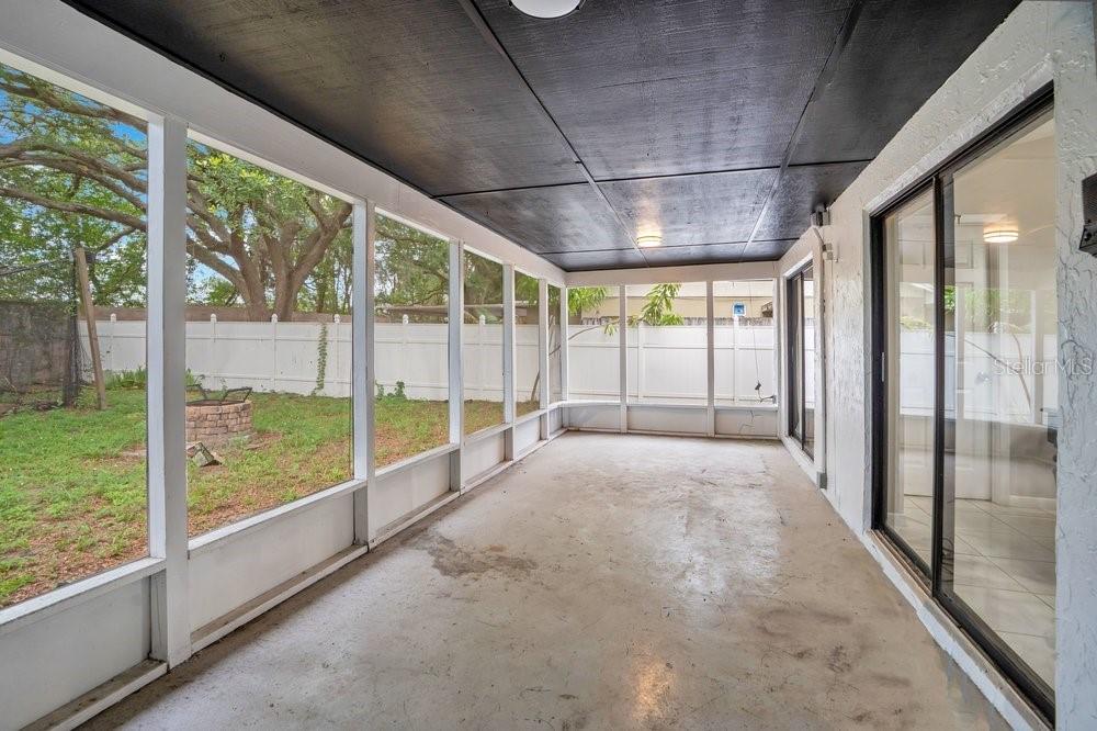 A screened-in porch with a dark ceiling, concrete floor, and sliding glass doors — 5533 PENTAIL CIRCLE, TAMPA, FL
