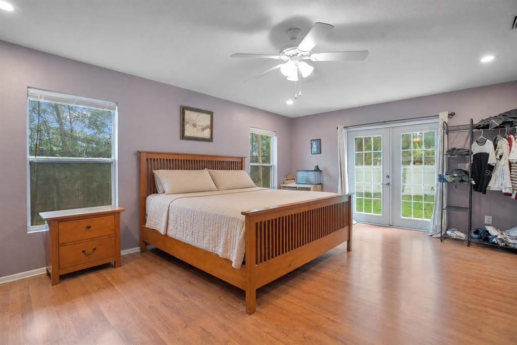 A bedroom with light purple walls, wood flooring, a wooden bed frame, and glass doors — 5533 PENTAIL CIRCLE, TAMPA, FL