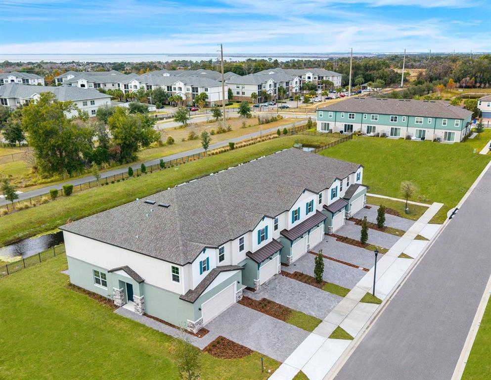 An aerial view shows a row of townhouses with attached garages and paved driveways — 1117 ORANGE TRAILSIDE WAY, OCOEE, FL