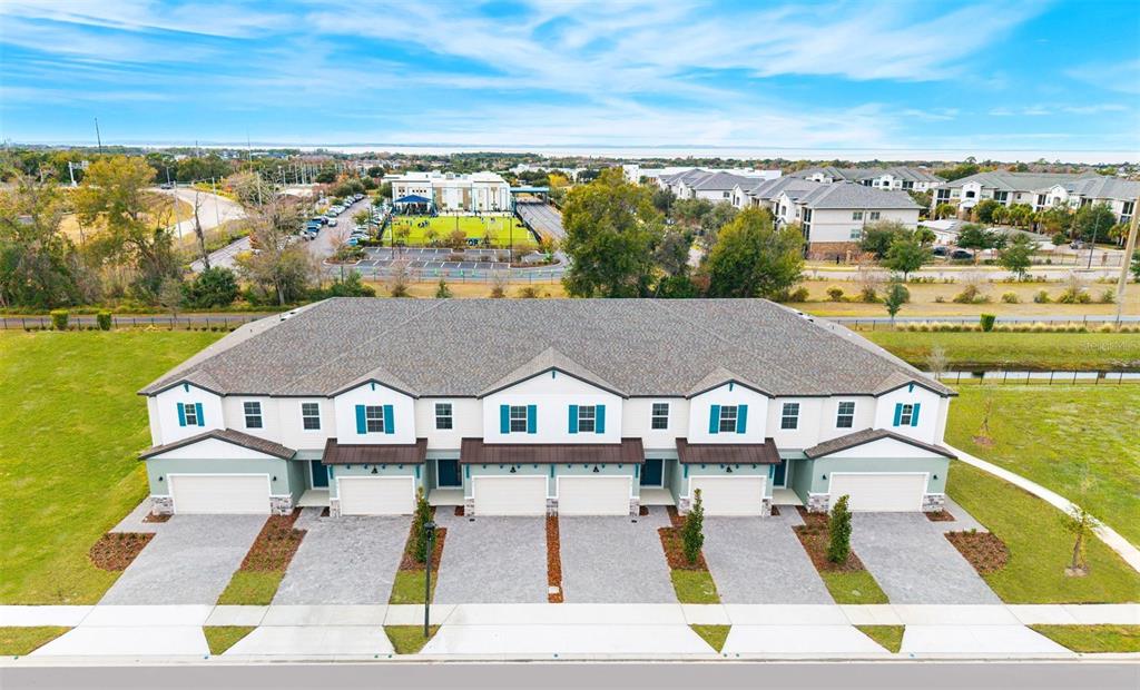 An aerial view of a multi-unit townhouse building with white siding, blue shutters, and garages — 1117 ORANGE TRAILSIDE WAY, OCOEE, FL