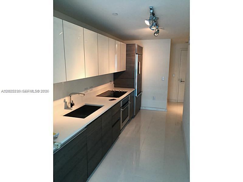 A modern kitchen features white upper cabinets, dark wood lower cabinets, and stainless steel appliances — 1100 S MIAMI AVE # 3306, Miami FL 33130, MIAMI, FL