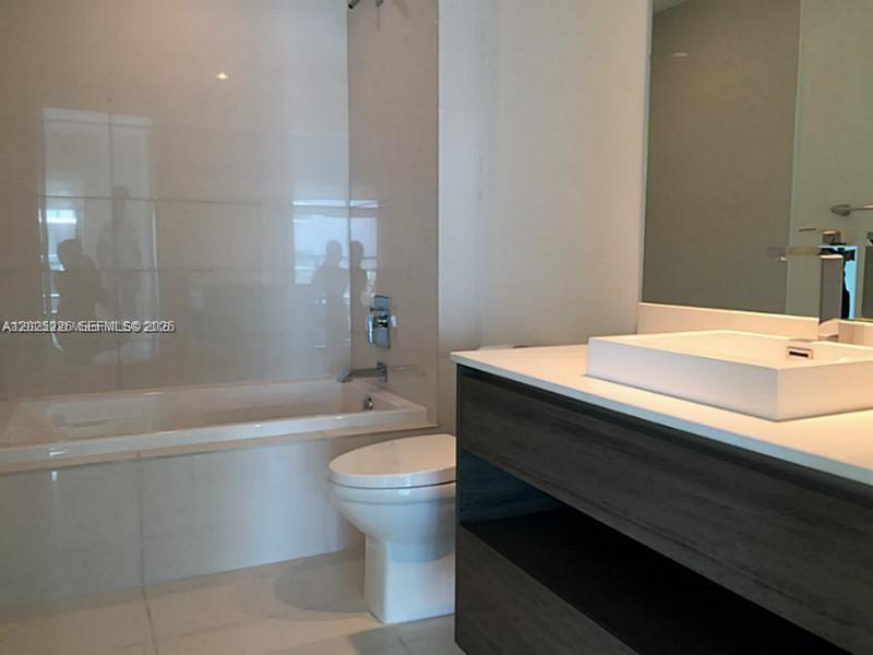 A modern bathroom features a white soaking tub, a toilet, and a dark wood vanity — 1100 S MIAMI AVE # 3306, Miami FL 33130, MIAMI, FL