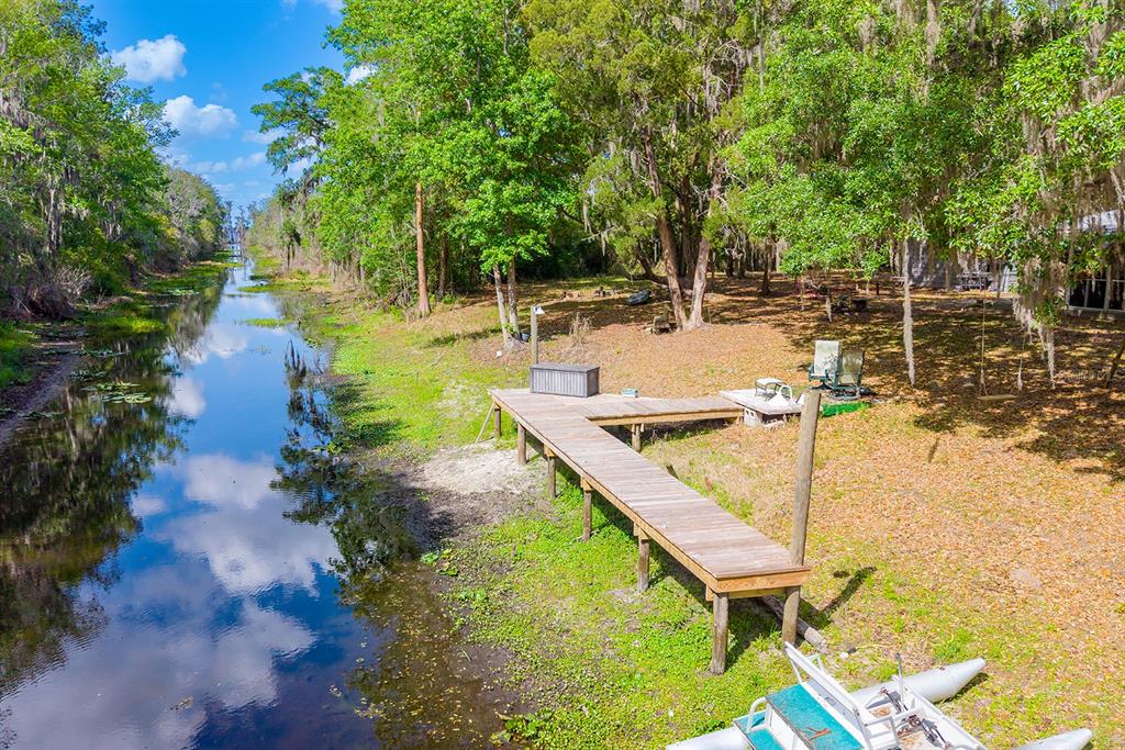 An aerial view of a wooden dock extending into a narrow canal surrounded by trees — 6308 ISLAND ROAD, MELROSE, FL