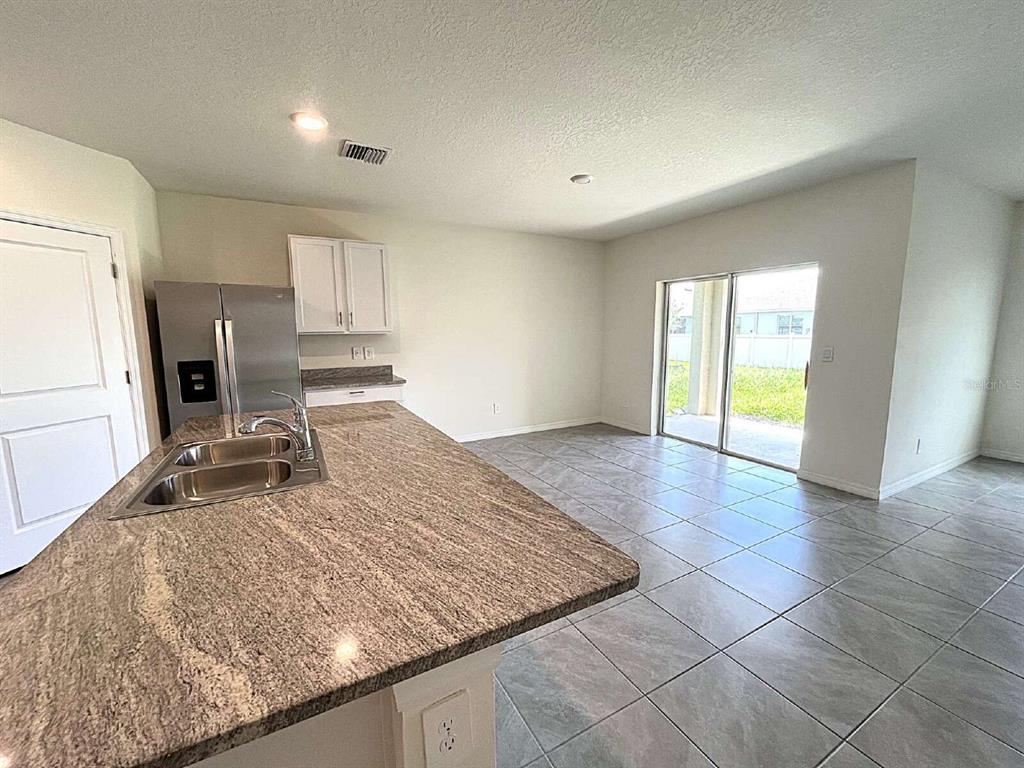 A kitchen with granite countertops and stainless steel appliances opens to a tiled dining area — 12724 LATERAL ROOT DRIVE, SARASOTA, FL