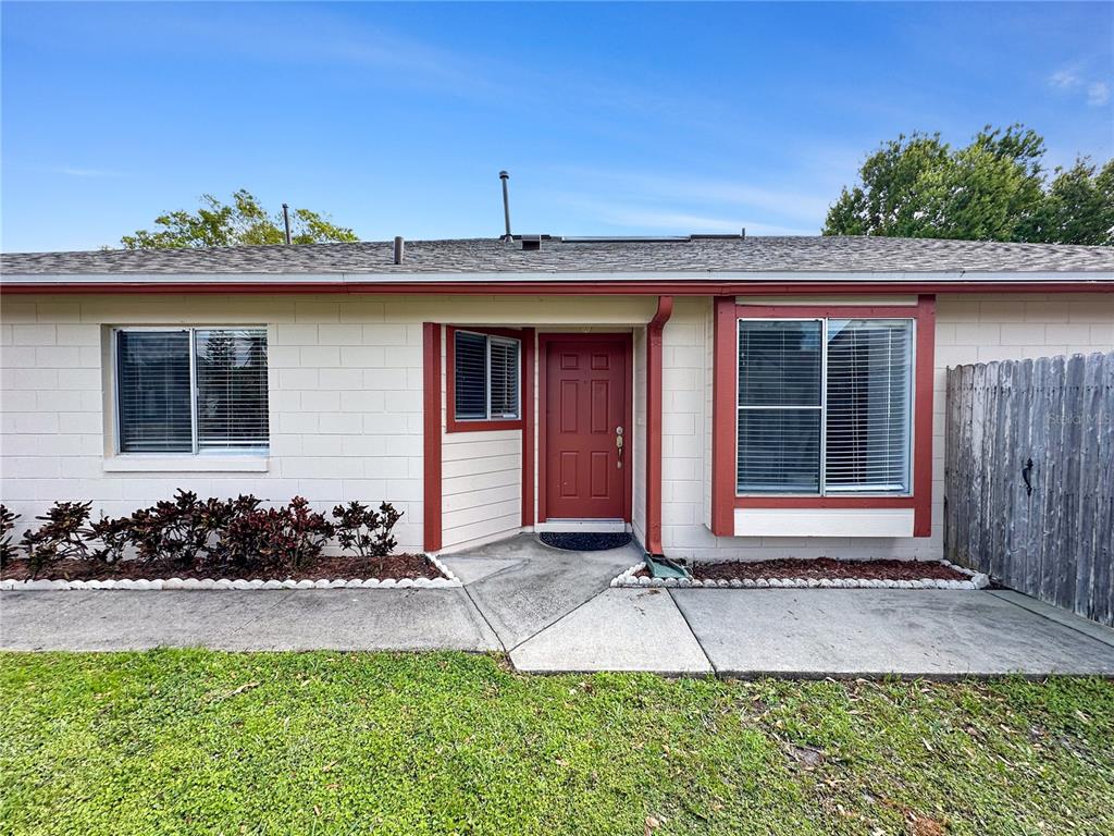 A single-story house exterior features a red front door, white block walls, and two windows — 2506 TOBIN COURT, ORLANDO, FL