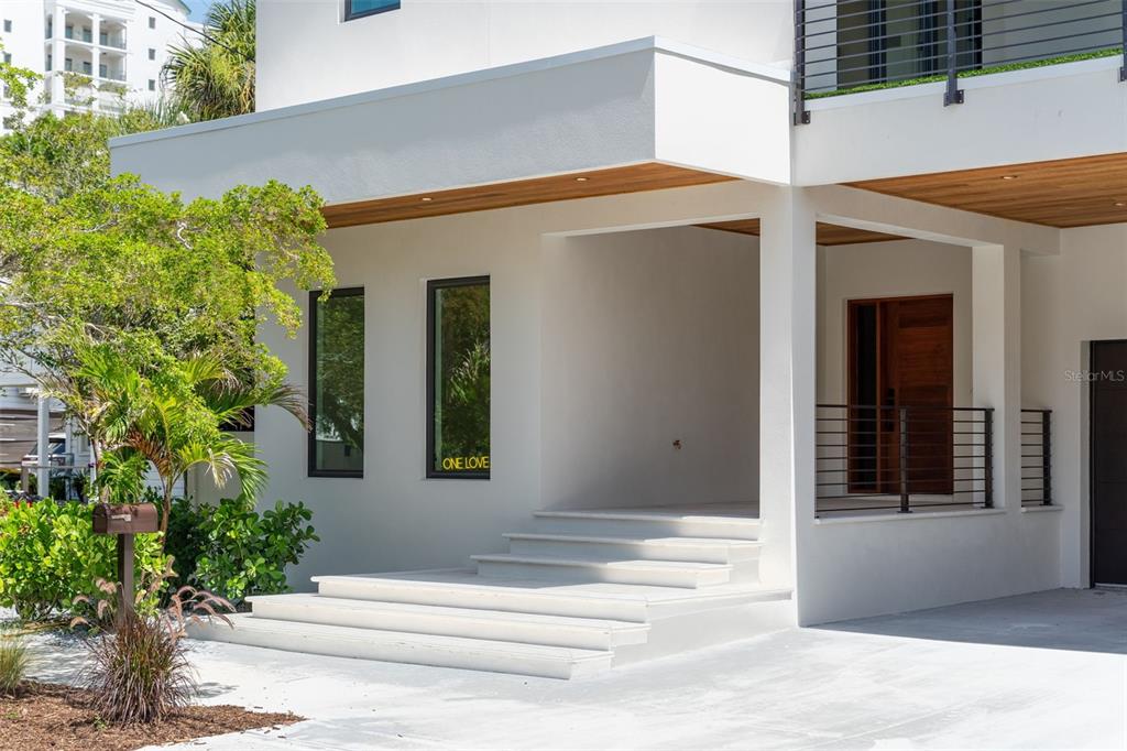 The exterior of a modern white house features a covered entryway with concrete steps — 1681 OAK STREET, SARASOTA, FL