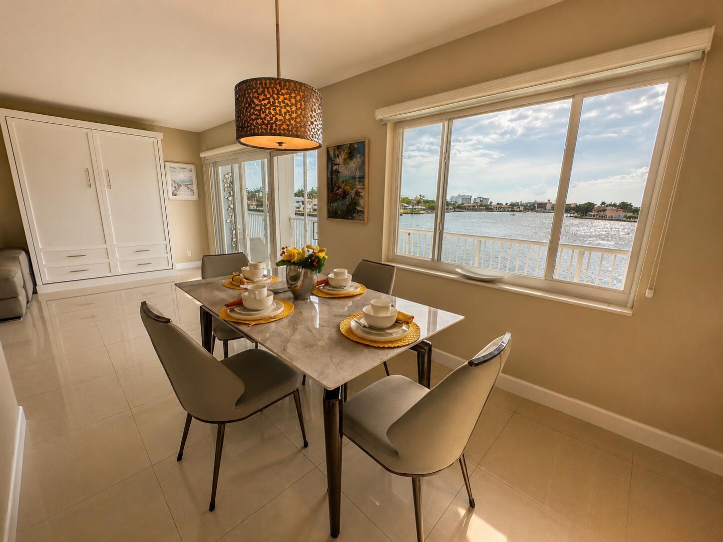 A dining room with a marble table, four chairs, and a large window overlooking water — 1201 S Riverside Drive # 307, Pompano Beach FL 33062, POMPANO BEACH, FL