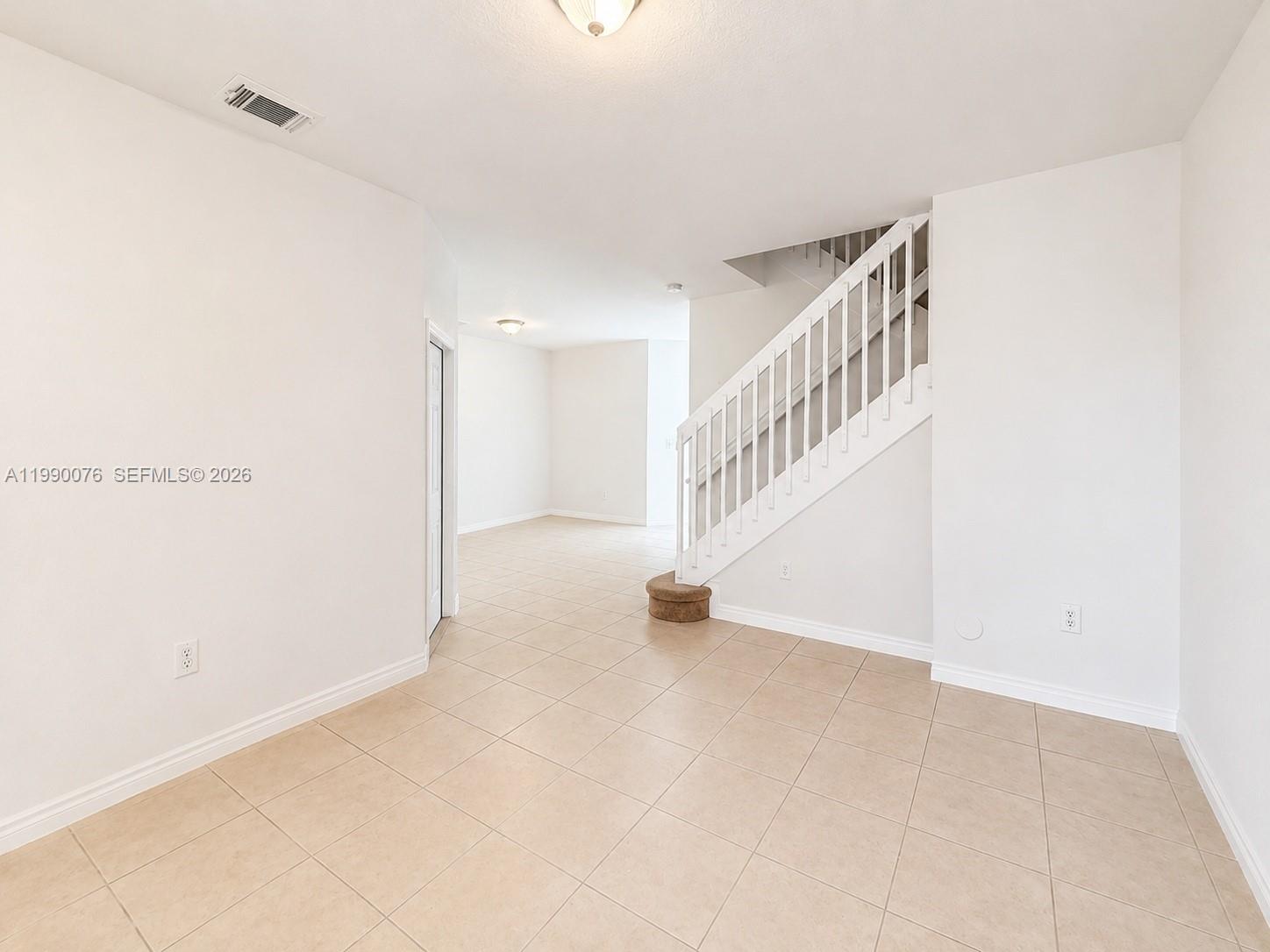 An empty room with beige tile flooring features a white staircase and recessed lighting — 16649 SW 80th Ter, Miami FL 33193, MIAMI, FL