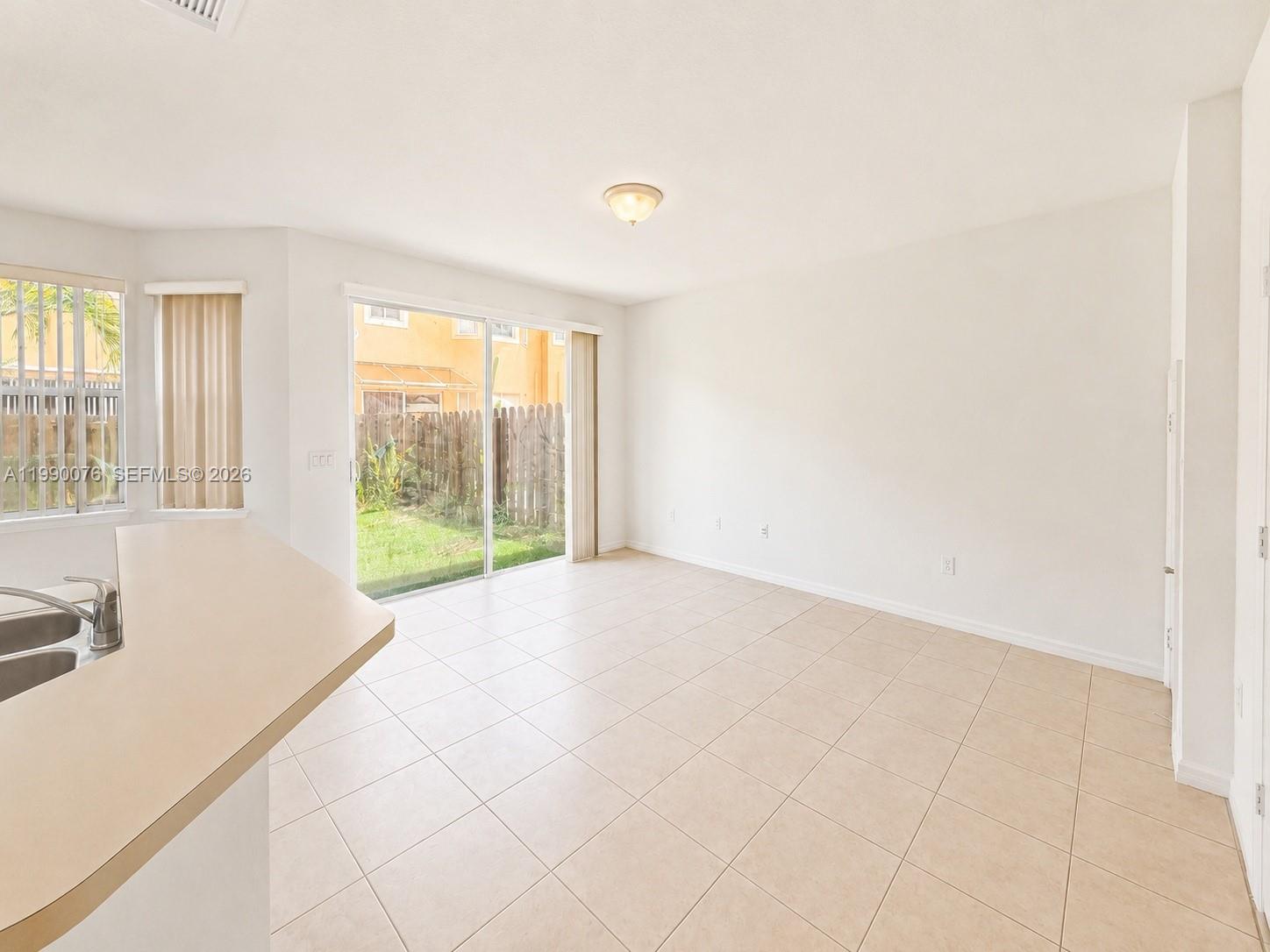 A bright, tiled living area features a sliding glass door leading to a fenced yard — 16649 SW 80th Ter, Miami FL 33193, MIAMI, FL