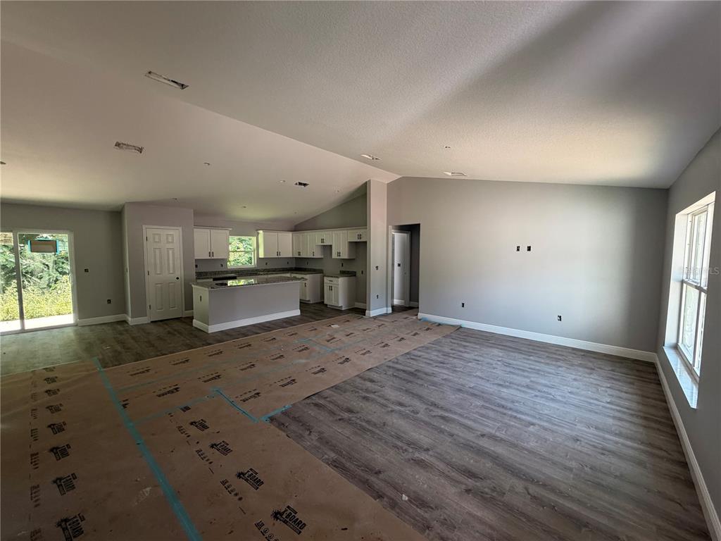 An open-concept living area features gray walls, wood-look flooring, and a kitchen with white cabinets — 865 SE 28TH STREET, OCALA, FL