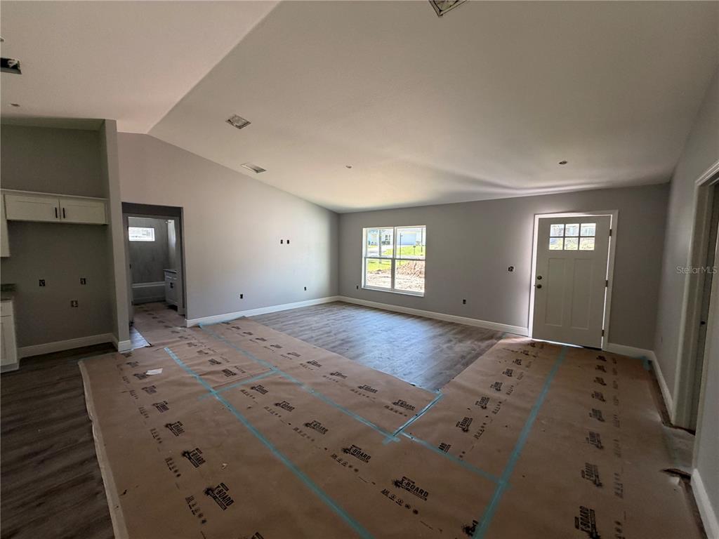 An open-concept living area features gray walls, wood-look flooring, and a door leading outside — 865 SE 28TH STREET, OCALA, FL