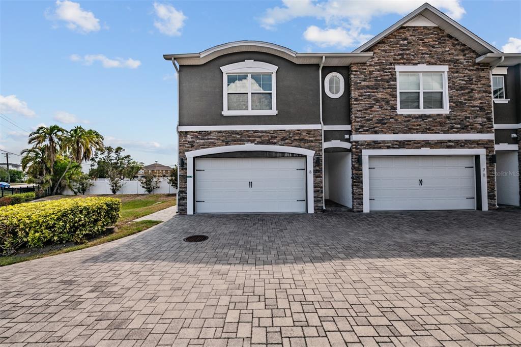 A two-story townhouse exterior features stone veneer, stucco, and two white garage doors — 6921 INTERBAY BOULEVARD UNIT 8, TAMPA, FL