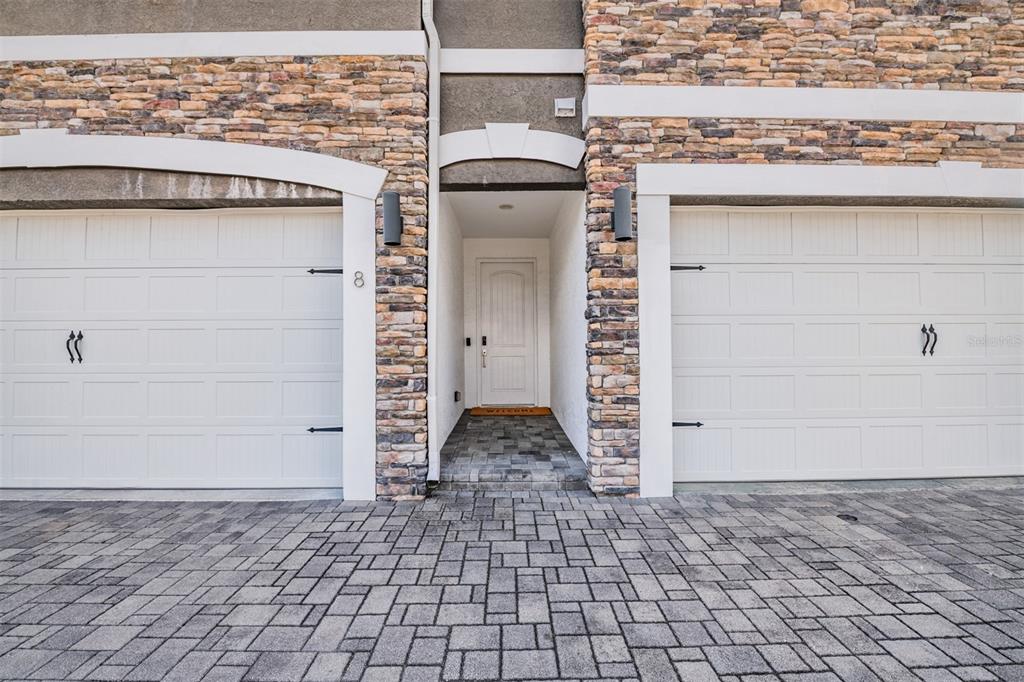 A stone-accented exterior features two white garage doors flanking a central recessed entryway — 6921 INTERBAY BOULEVARD UNIT 8, TAMPA, FL