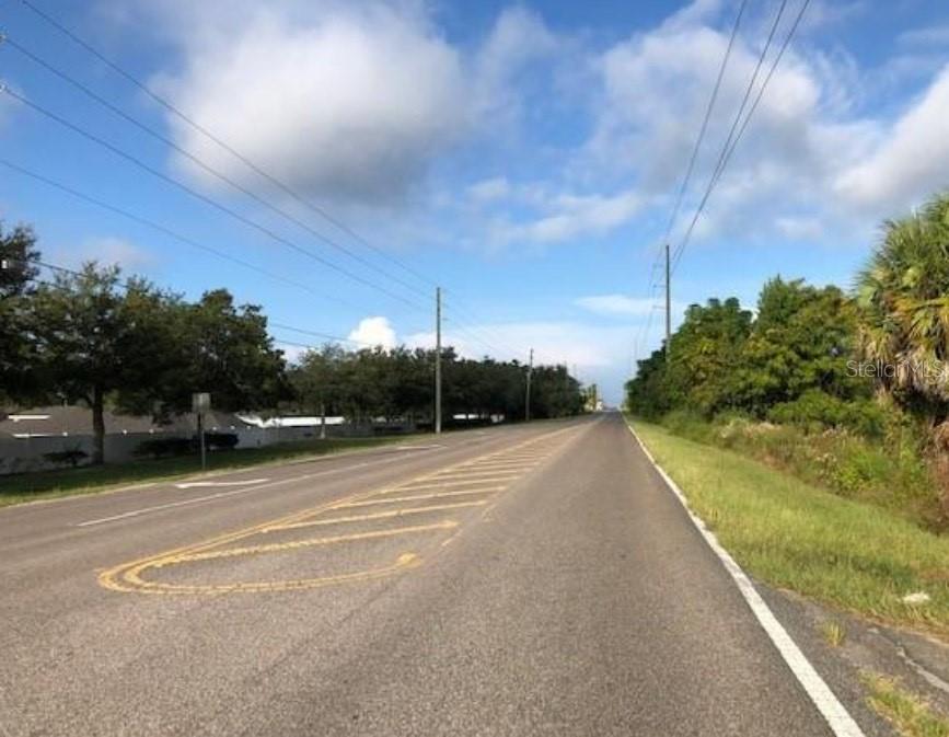 A paved road stretches into the distance under a blue sky with scattered clouds — 9221 NEW YORK AVENUE, HUDSON, FL