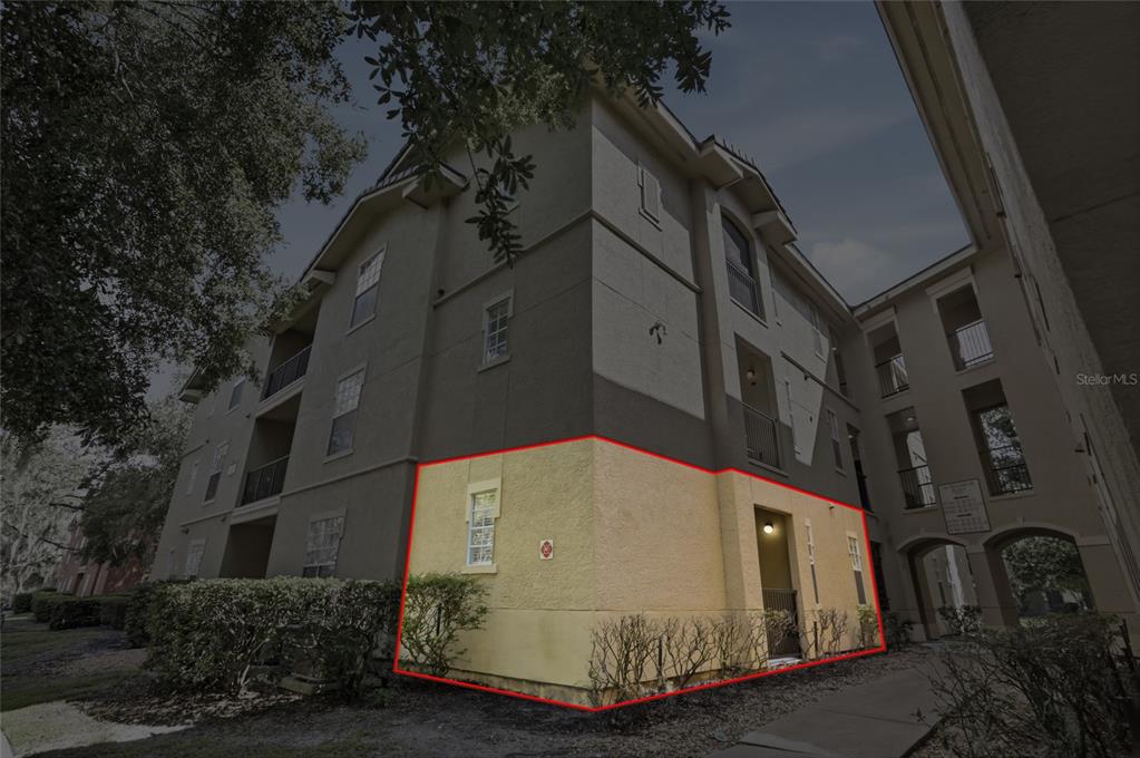 A large yellow building with a central tower stands behind a circular fountain and landscaping — 114 VISTA VERDI CIRCLE UNIT 112, LAKE MARY, FL