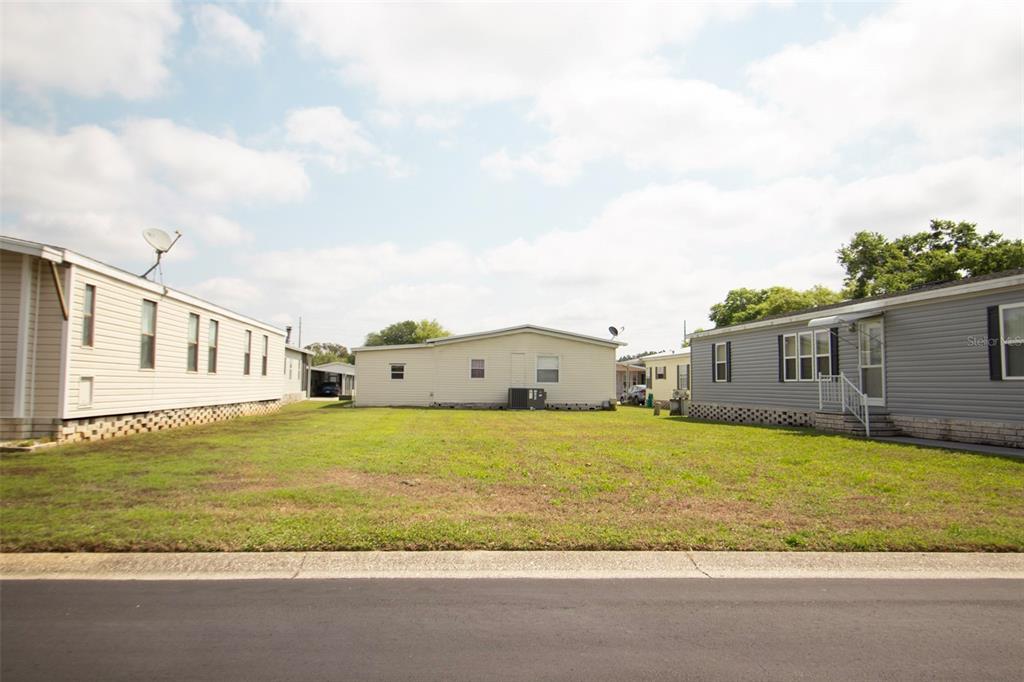 A grassy lot sits between two manufactured homes under a cloudy sky — 3024 BRIAR STREET, WESLEY CHAPEL, FL