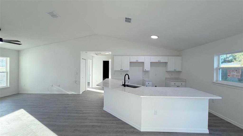 A kitchen with white cabinets and a peninsula island overlooks an open-concept living area — 2990 TIMBERLAKE, DUNNELLON, FL