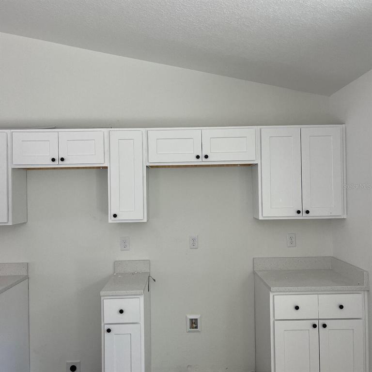 A kitchen features white shaker-style cabinets, light countertops, and white walls — 2990 TIMBERLAKE, DUNNELLON, FL