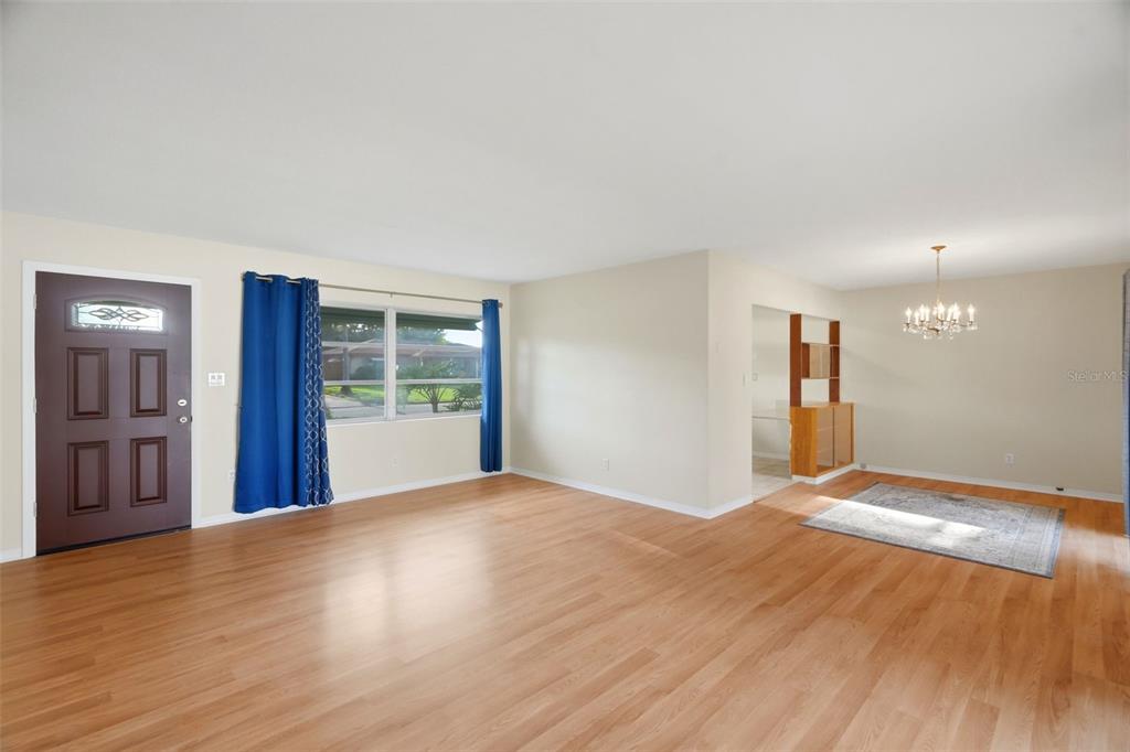 A living and dining area with light wood flooring, a front door, and a chandelier — 8835 109TH STREET, SEMINOLE, FL