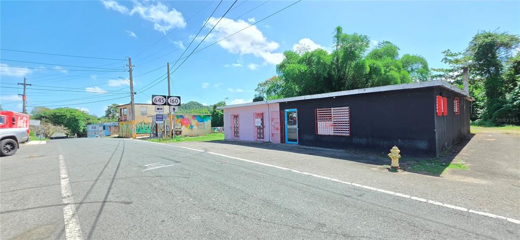 A single-story commercial building with a black and pink exterior sits at a road intersection — Carr #160 W ALMIRANTE, VEGA BAJA, PR