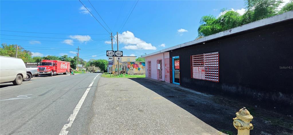 A street-level view shows a black and pink building next to a road with signage — Carr #160 W ALMIRANTE, VEGA BAJA, PR