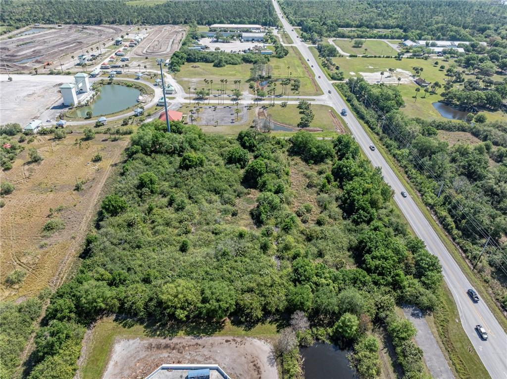 An aerial view shows a large, wooded lot adjacent to a road and a pond — 0 Unassigned, Fellsmere FL 32948, FELLSMERE, FL