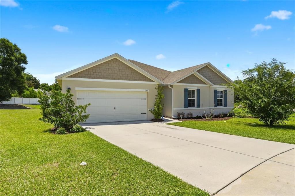 A single-story house with a beige exterior, a two-car garage, and a concrete driveway — 203 AUBURN GROVE BOULEVARD, AUBURNDALE, FL