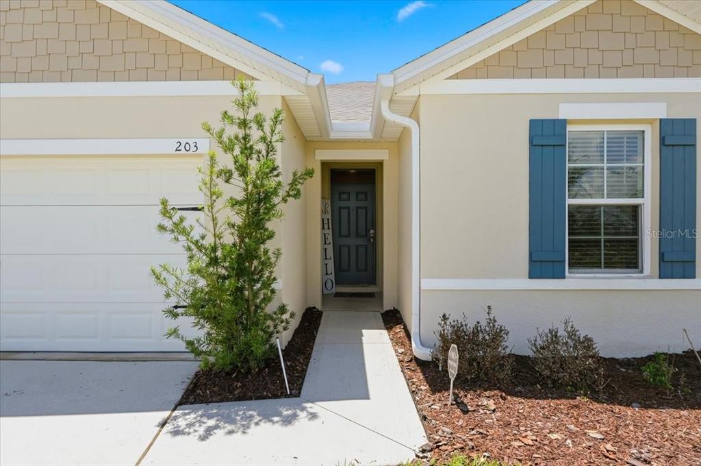 The exterior of a house features a garage, a front door, and a walkway — 203 AUBURN GROVE BOULEVARD, AUBURNDALE, FL