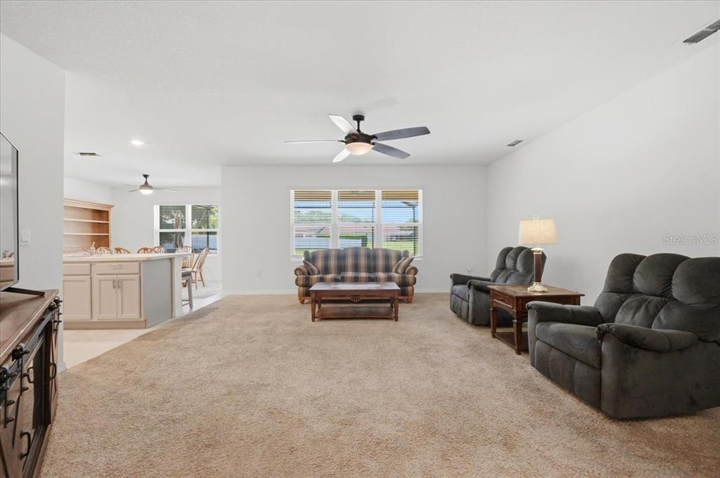 A living room with beige carpeting, a plaid sofa, and two dark gray recliners — 203 AUBURN GROVE BOULEVARD, AUBURNDALE, FL