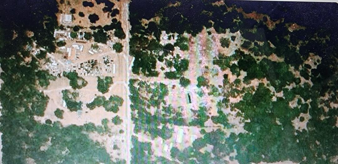 This aerial view shows a rural property with scattered buildings, trees, and a dirt road — 0000 SE Thomas Way, FL 32059, FL
