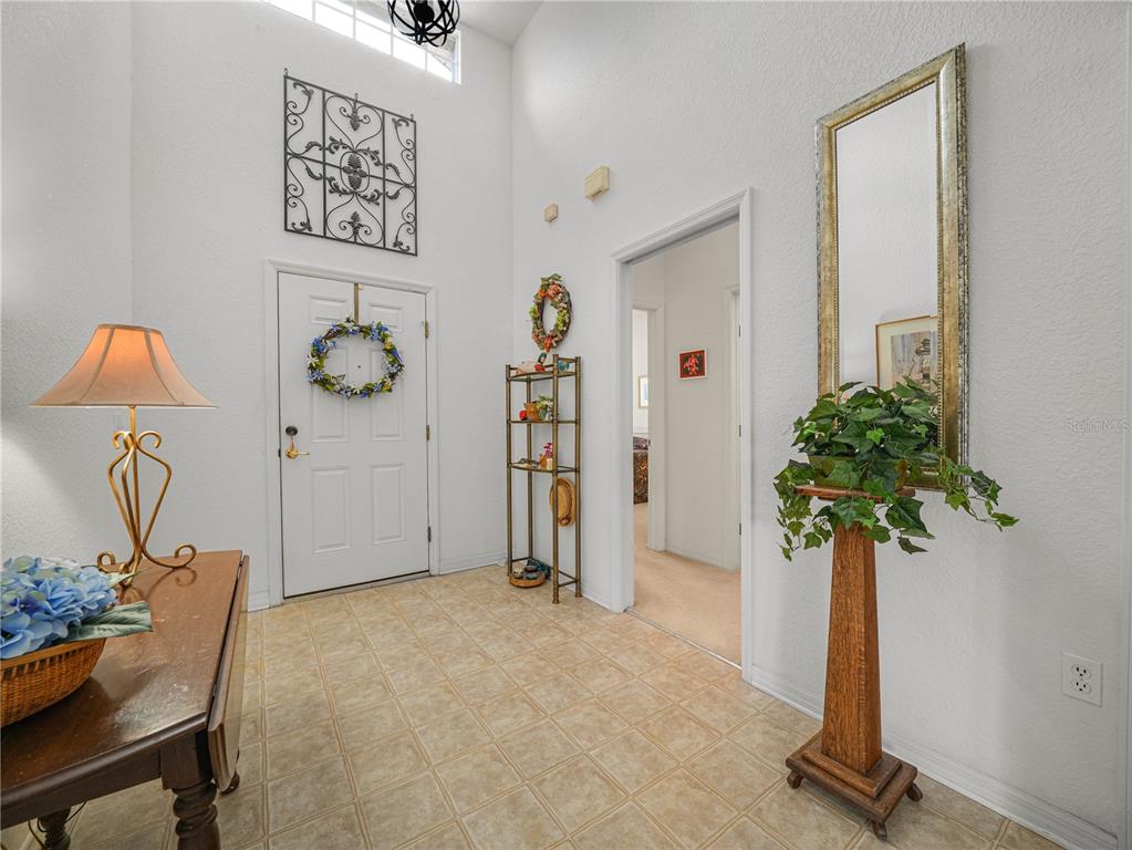 A bright entryway features tiled floors, a high ceiling, a front door, and decorative furniture — 4251 DORNOCH DRIVE, LAKE WALES, FL