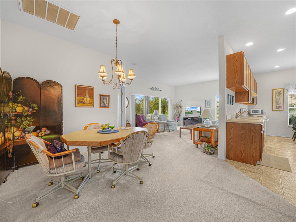 A dining area with a chandelier and a folding screen opens into a living room — 4251 DORNOCH DRIVE, LAKE WALES, FL