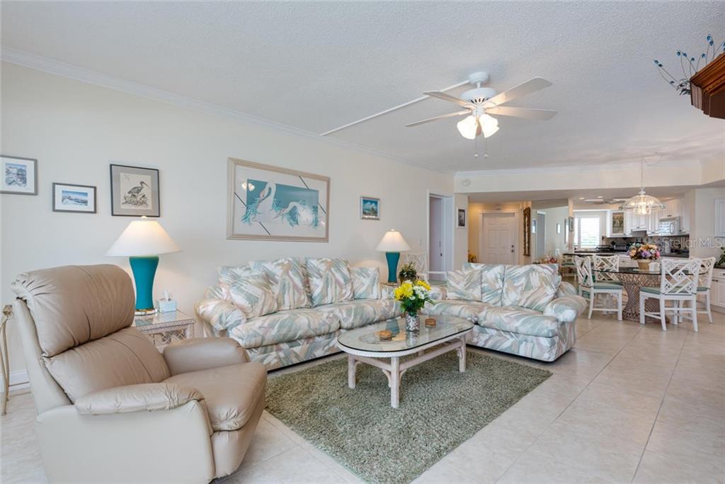 A living room features tile floors, a floral sofa set, and a beige recliner — 4825 GULF OF MEXICO DRIVE UNIT 605, LONGBOAT KEY, FL
