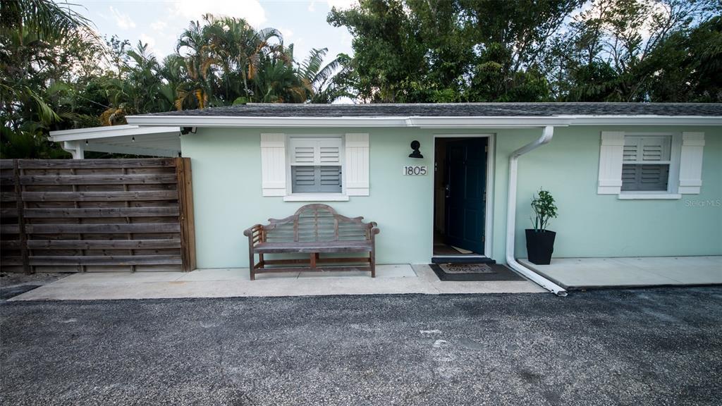 A light green house exterior features a wooden bench, a dark door, and white shutters — 1805 IVANHOE STREET, SARASOTA, FL