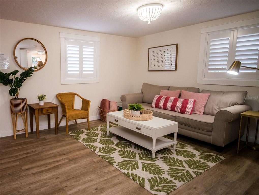 A living room features a beige sofa, white coffee table, wicker chair, and patterned rug — 1805 IVANHOE STREET, SARASOTA, FL