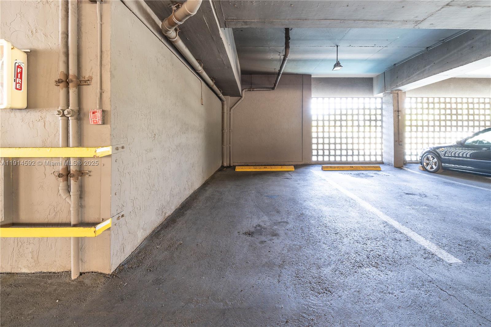 A concrete parking garage space features a fire alarm box and yellow safety bumpers — 2600 Collins Ave # 308, Miami Beach FL 33140, MIAMI BEACH, FL