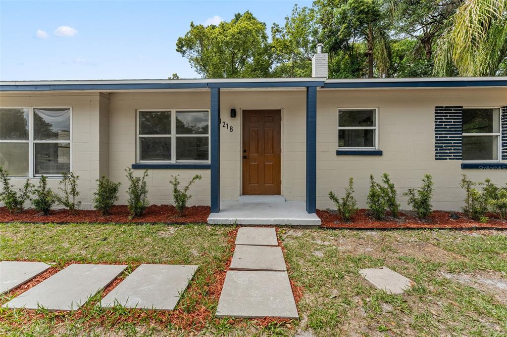 A single-story house with a carport, tan siding, and a large grassy yard — 1218 CRESCENT STREET, SANFORD, FL