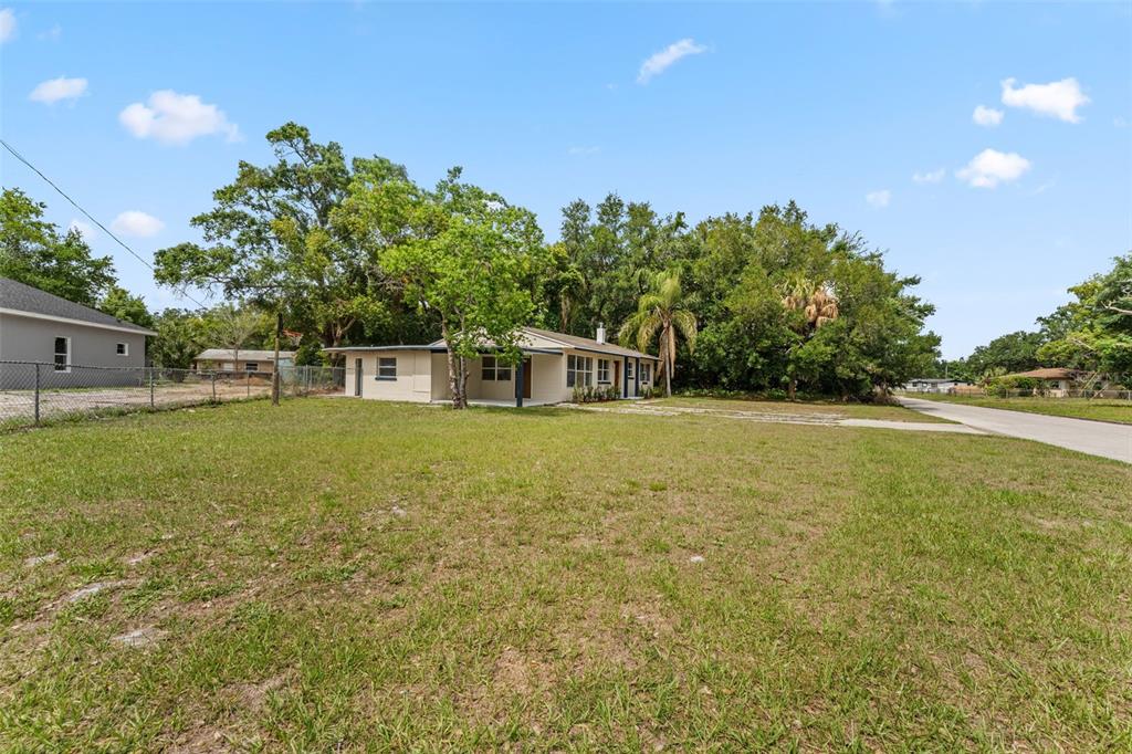 An open-concept room features light wood-look flooring, a ceiling fan, and a white kitchen island — 1218 CRESCENT STREET, SANFORD, FL