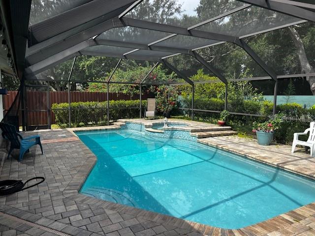 A screened-in backyard features a rectangular swimming pool with a raised spa and brick pavers — 18330 CYPRESS VIEW WAY, TAMPA, FL