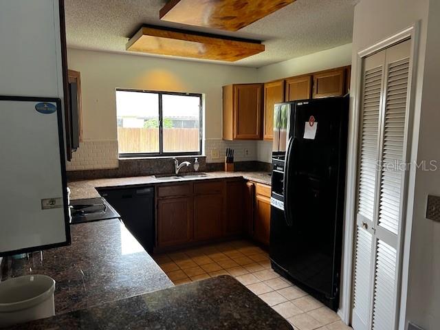 A kitchen features wood cabinets, a black refrigerator, a window over the sink, and tile flooring — 18330 CYPRESS VIEW WAY, TAMPA, FL
