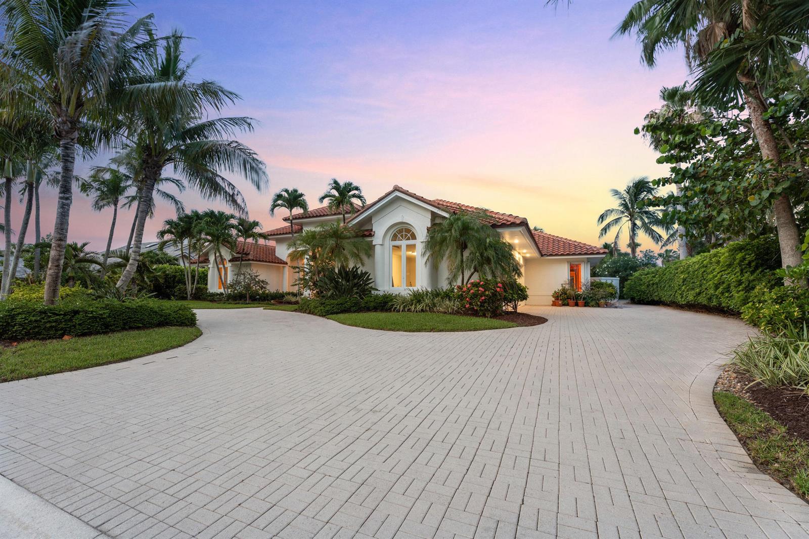 A single-story house with a tiled roof and a large paved driveway at sunset — 6841 SE Harbor Circle, Stuart FL 34996, STUART, FL