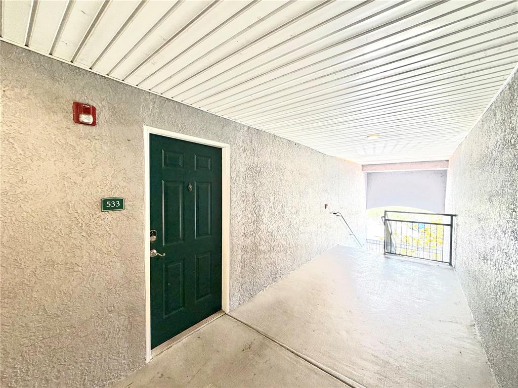 A dark green apartment door labeled 533 is located in a concrete outdoor hallway — 18001 RICHMOND PLACE DRIVE UNIT 533, TAMPA, FL