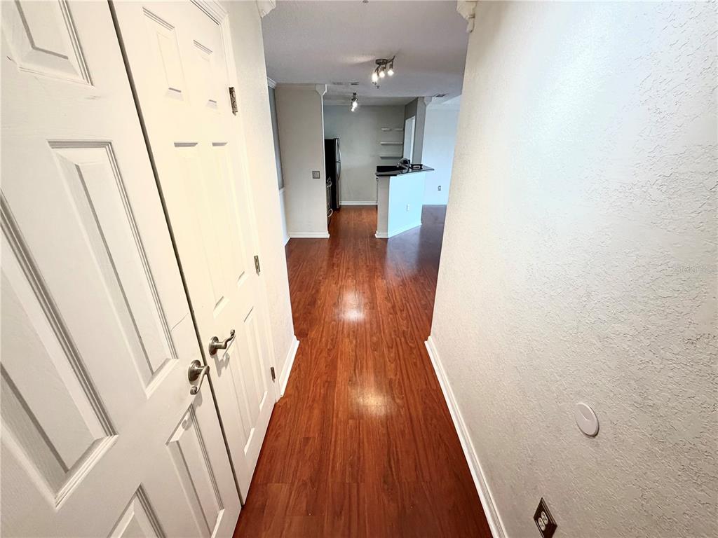 A hallway with wood-look flooring leads toward an open kitchen with a breakfast bar — 18001 RICHMOND PLACE DRIVE UNIT 533, TAMPA, FL