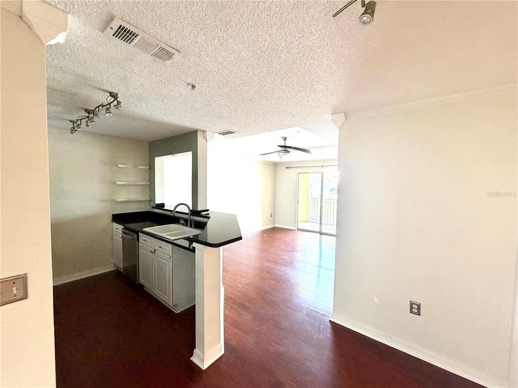 An open-concept kitchen with dark countertops overlooks a living area with wood-look flooring — 18001 RICHMOND PLACE DRIVE UNIT 533, TAMPA, FL