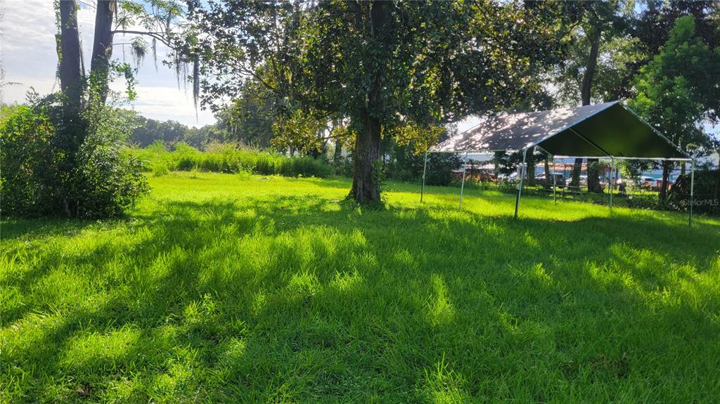 A grassy backyard features a large mature tree and a metal-framed canopy tent — 1521 NW 27TH AVENUE, OCALA, FL