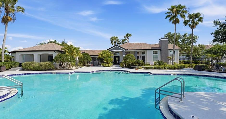A swimming pool sits in front of a single-story building with palm trees — 1015 OHANA WAY, NORTH PORT, FL