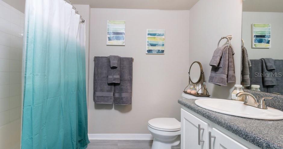 A bathroom features a teal ombre shower curtain, gray towels, and a white vanity — 1015 OHANA WAY, NORTH PORT, FL