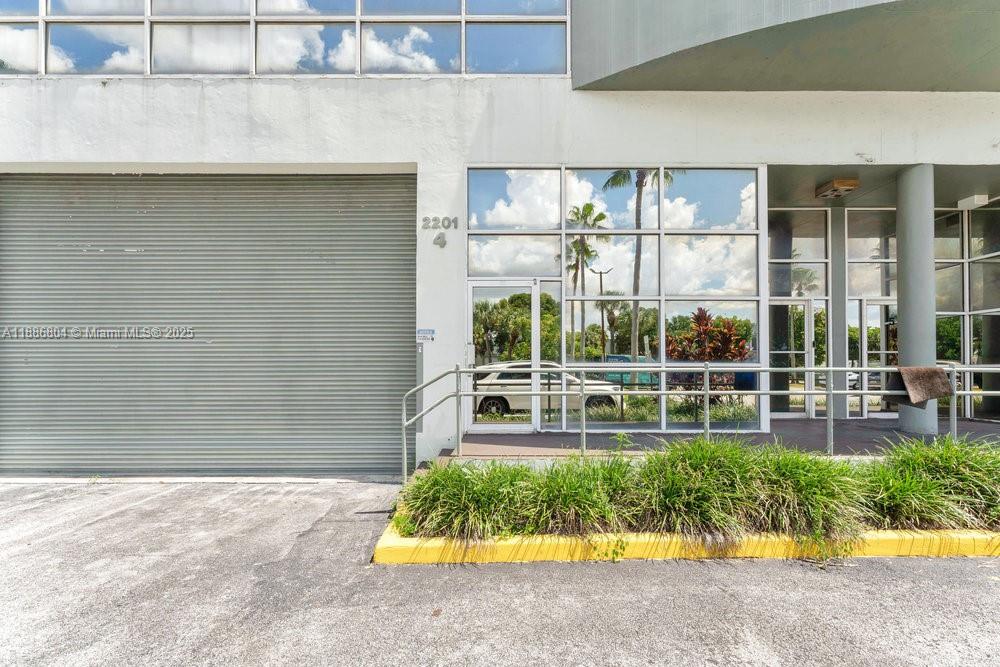 The exterior of a commercial building features a metal roll-up door and glass entrance — 2201 NW 102nd Pl # 4A, Doral FL 33172, DORAL, FL